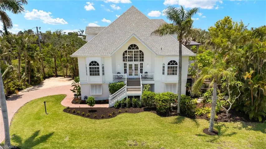 View of front of home with stairway, french doors, a front lawn, a shingled roof, and a balcony