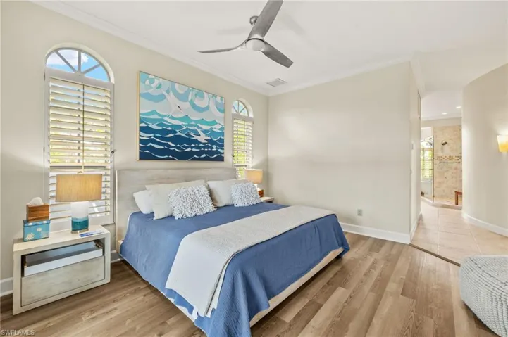 Primate bedroom featuring ornamental molding, light wood-style floors, and multiple windows