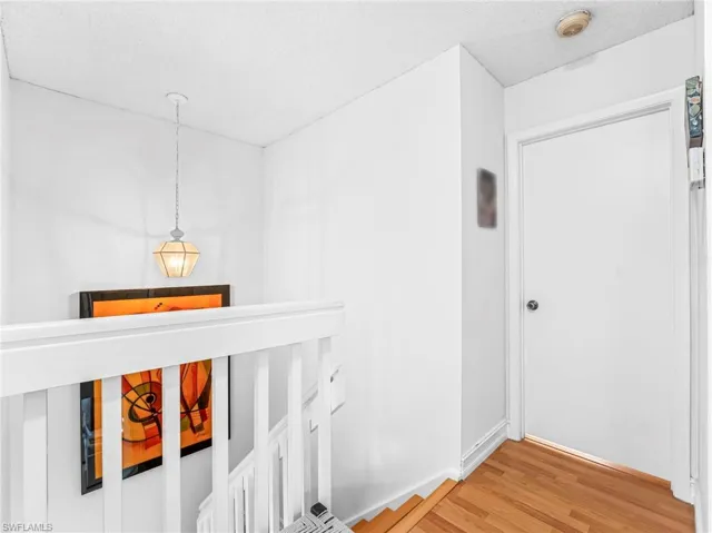 Corridor with light wood-style flooring and a textured ceiling