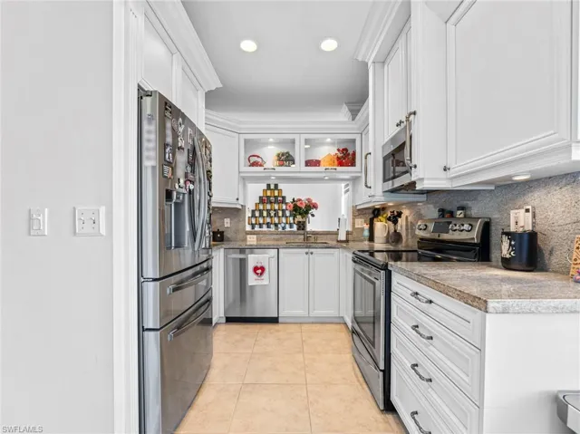 Kitchen featuring stainless steel appliances, white cabinets, tasteful backsplash, light tile patterned floors, and recessed lighting