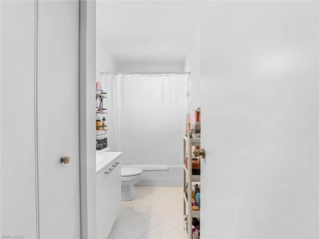 Full bath featuring vanity, light tile patterned floors, and shower / bathtub combination with curtain