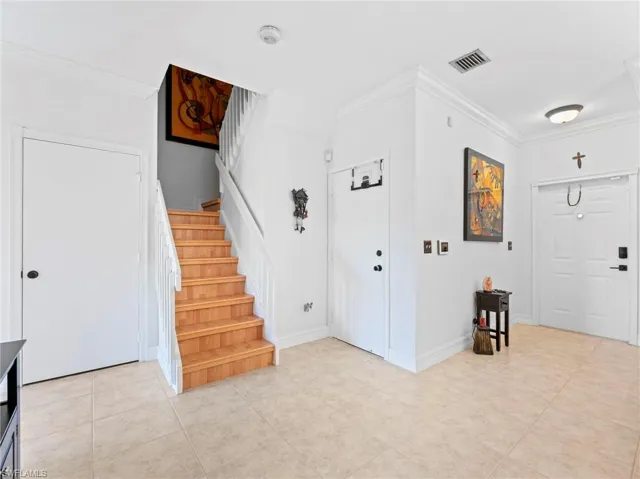Entryway featuring ornamental molding and light tile patterned flooring