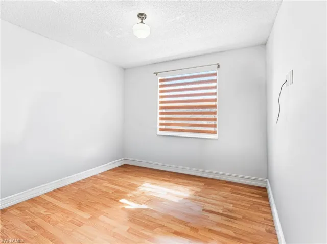 Spare room featuring light wood-type flooring and a textured ceiling