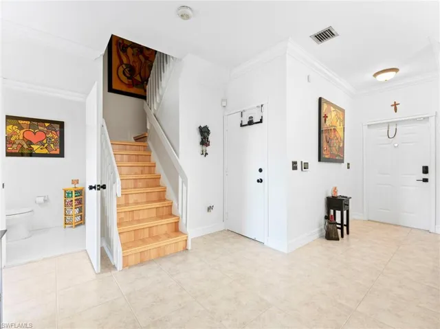 Foyer with ornamental molding and light tile patterned flooring