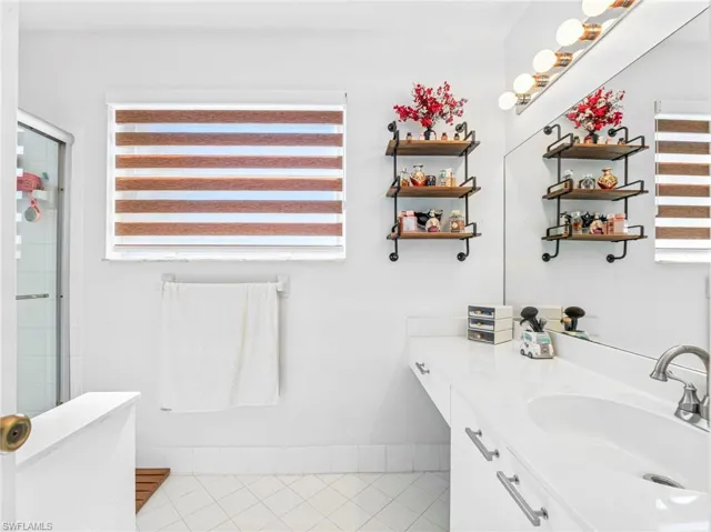 Full bathroom featuring vanity, a stall shower, and light tile patterned flooring