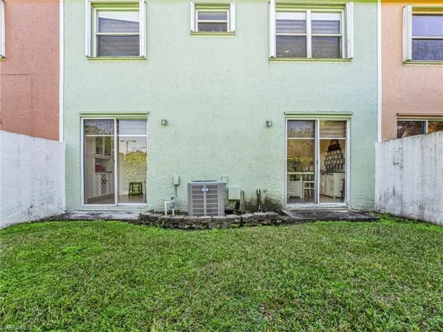Rear view of property featuring a yard and stucco siding