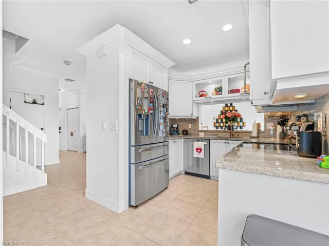 Kitchen with ornamental molding, white cabinets, stainless steel appliances, tasteful backsplash, and light tile patterned flooring
