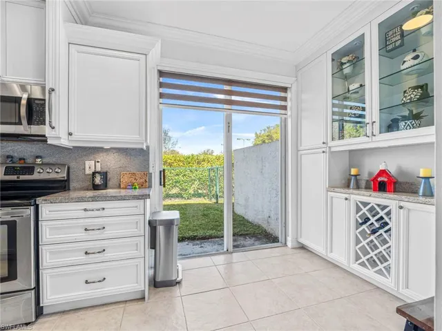 Bar with stainless steel appliances, white cabinets, light stone countertops, and ornamental molding
