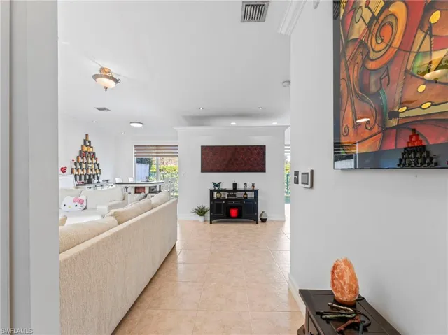 Living room featuring light tile patterned flooring, ornamental molding, and recessed lighting