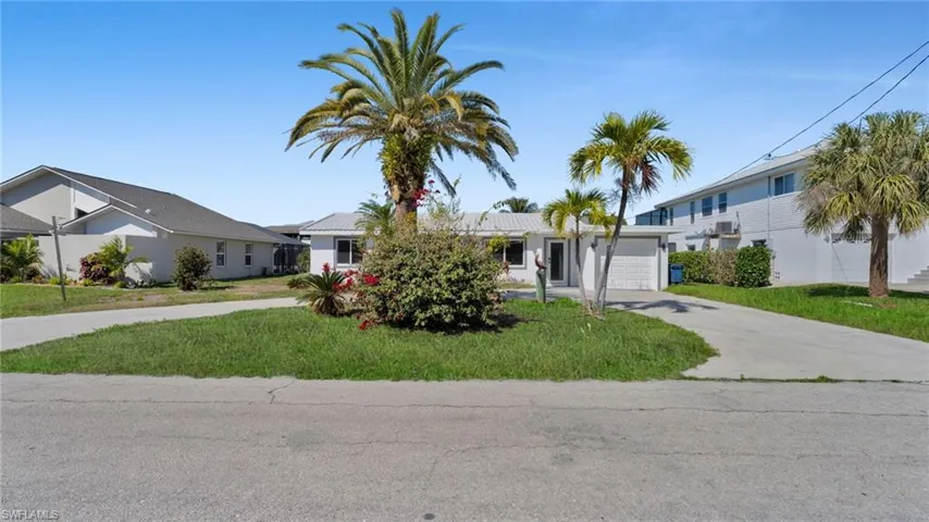 View of front of property with a front yard, driveway, and an attached garage
