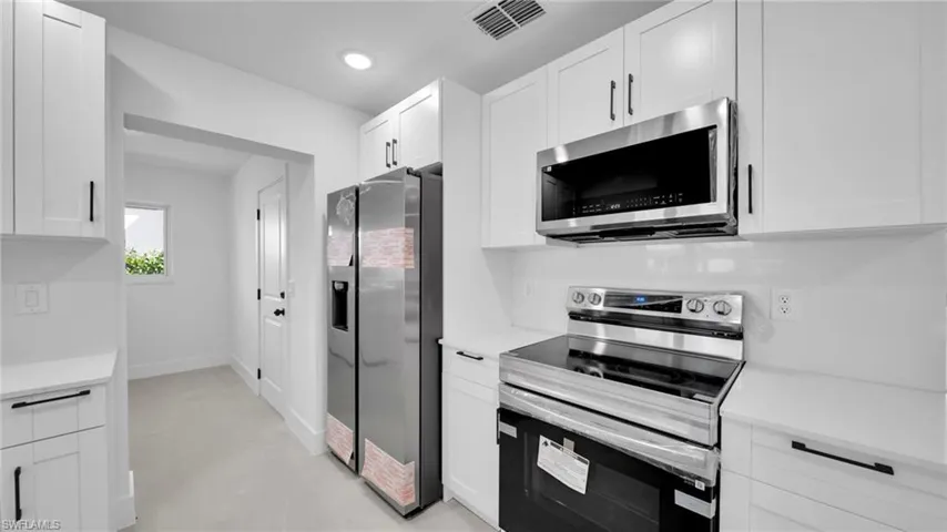 Kitchen featuring stainless steel appliances, white cabinets, concrete flooring, and recessed lighting