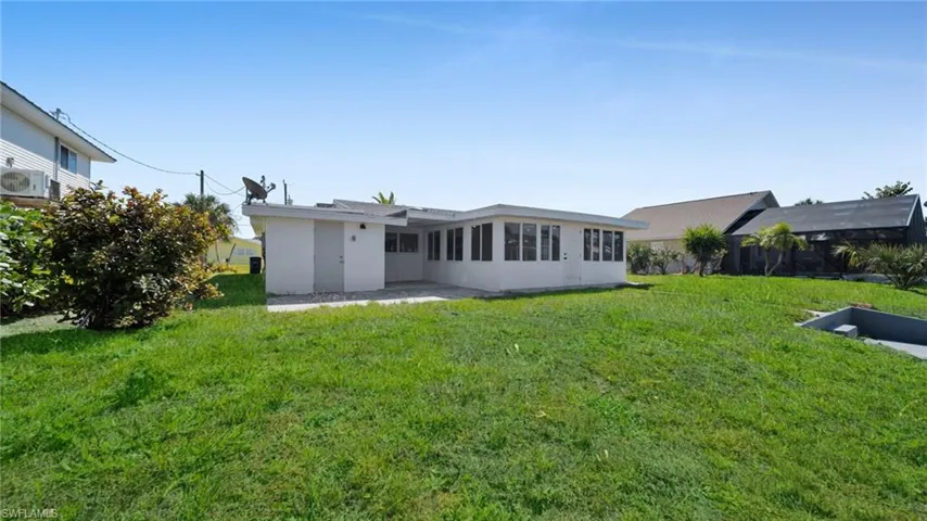 Rear view of house featuring a patio, a lawn, and stucco siding
