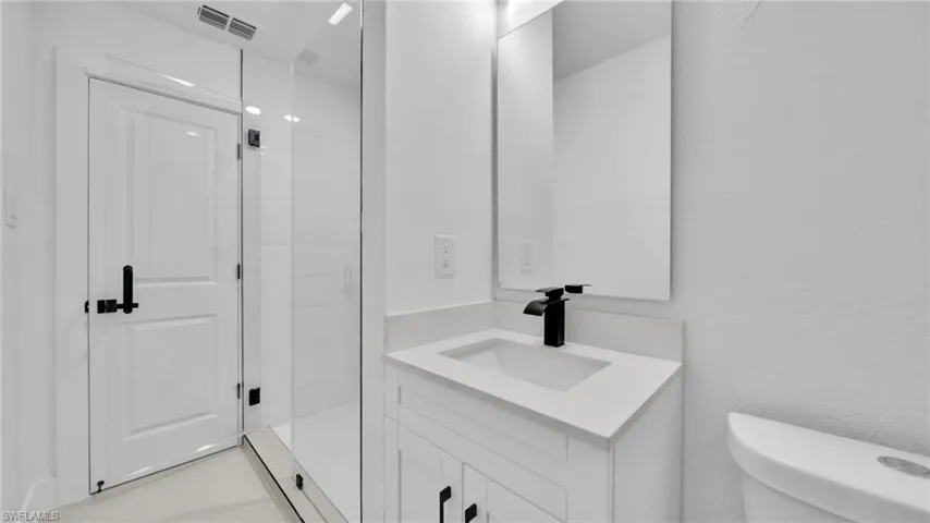Bathroom with vanity, a stall shower, and a textured wall