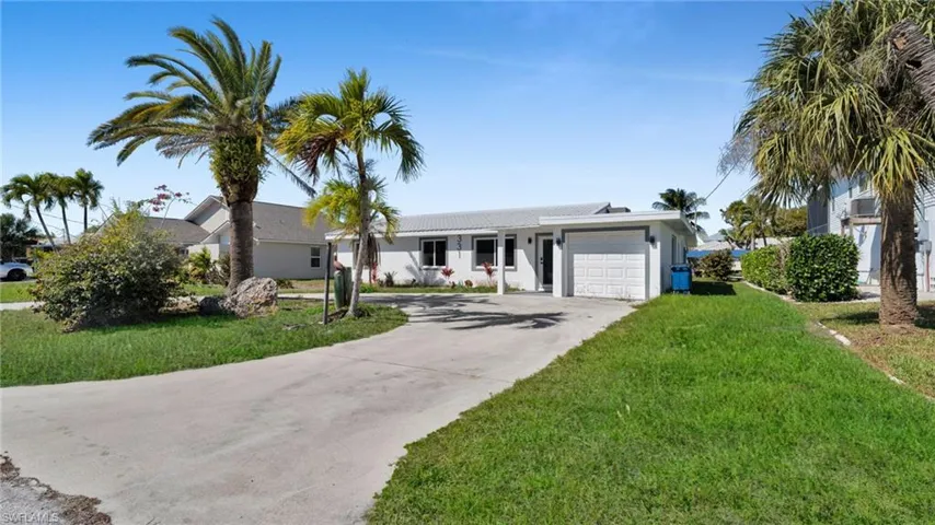 Ranch-style house featuring a front lawn, driveway, an attached garage, and stucco siding