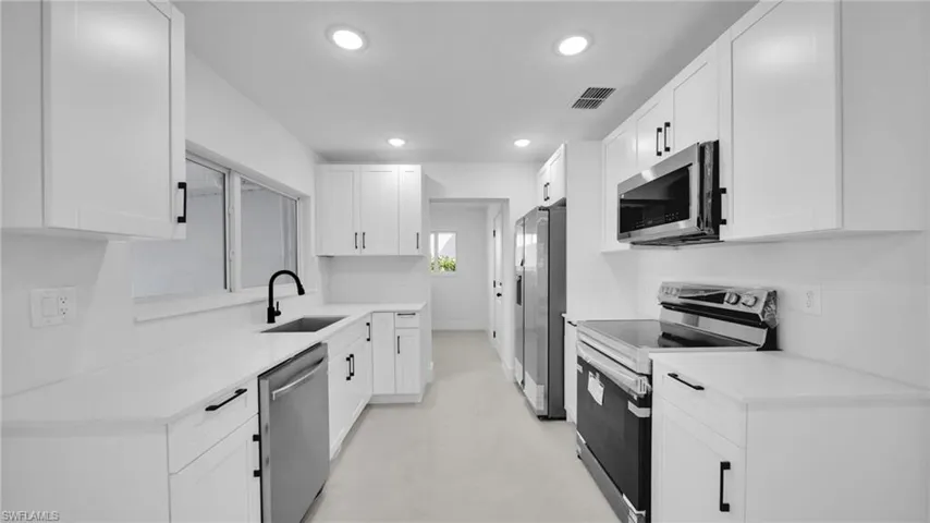 Kitchen featuring stainless steel appliances, white cabinetry, recessed lighting, and light stone counters
