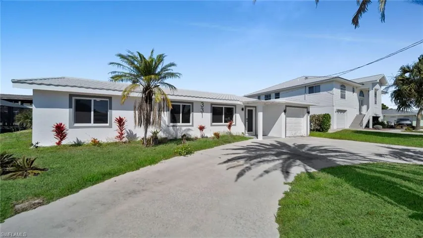 View of front facade featuring driveway, a front lawn, and stucco siding