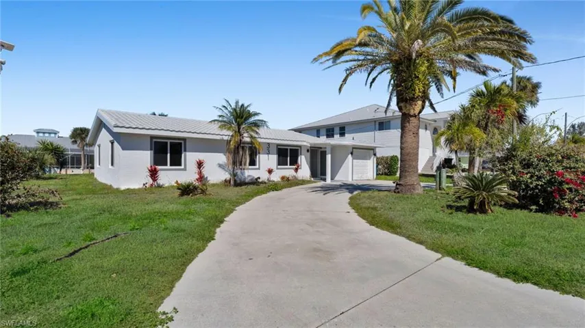 View of front of property with a front yard, concrete driveway, stucco siding, and a garage