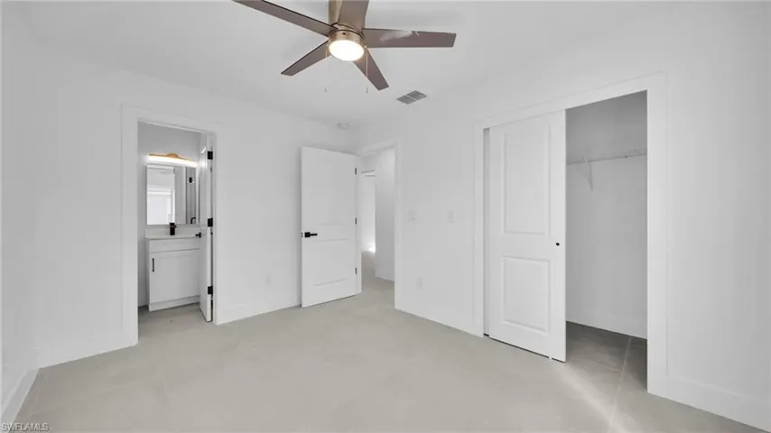 Unfurnished bedroom with a closet, ceiling fan, and connected bathroom