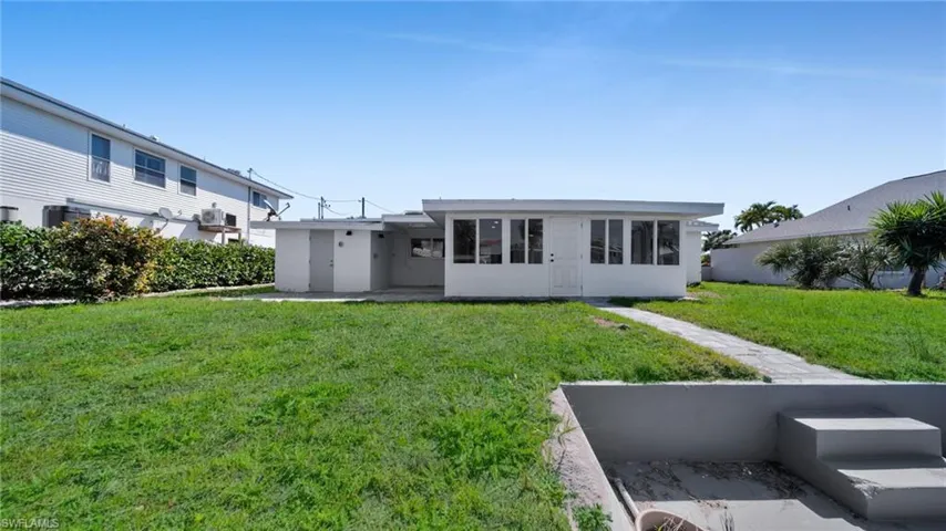 Rear view of property with a yard and stucco siding