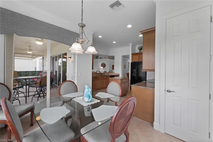 Tiled dining room with ceiling fan with notable chandelier and ornamental molding