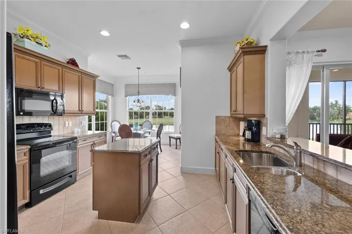 Kitchen with tasteful backsplash, black appliances, sink, decorative light fixtures, and a kitchen island