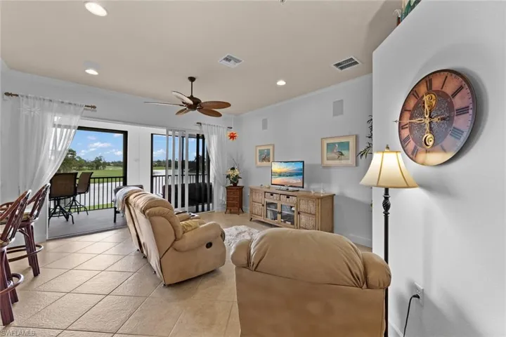 Tiled living room featuring ceiling fan and ornamental molding