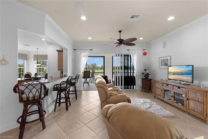 Tiled living room with ceiling fan and crown molding