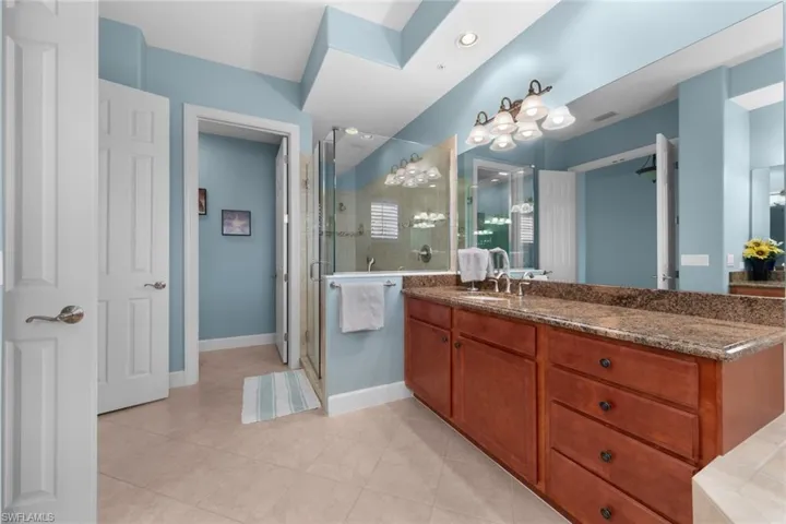 Bathroom with tile patterned floors, a shower with door, and vanity