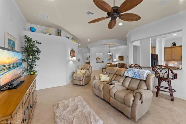 Living room featuring ornamental molding, light tile patterned floors, and ceiling fan
