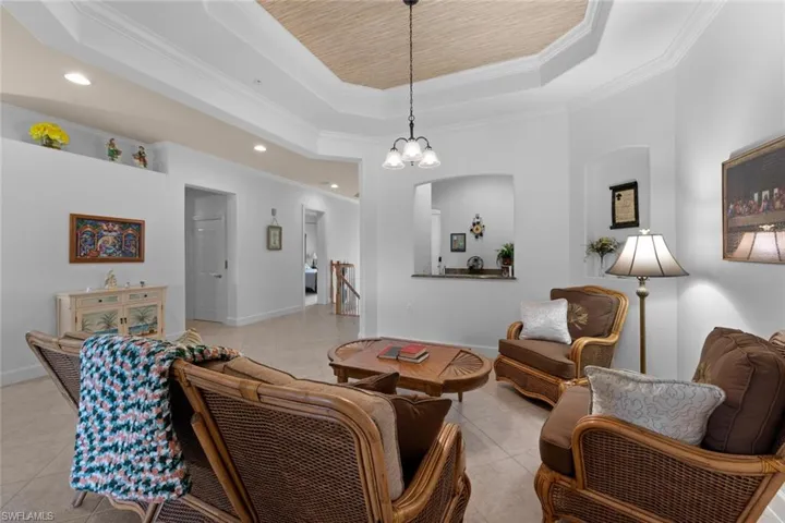Tiled living room featuring an inviting chandelier, crown molding, and a tray ceiling