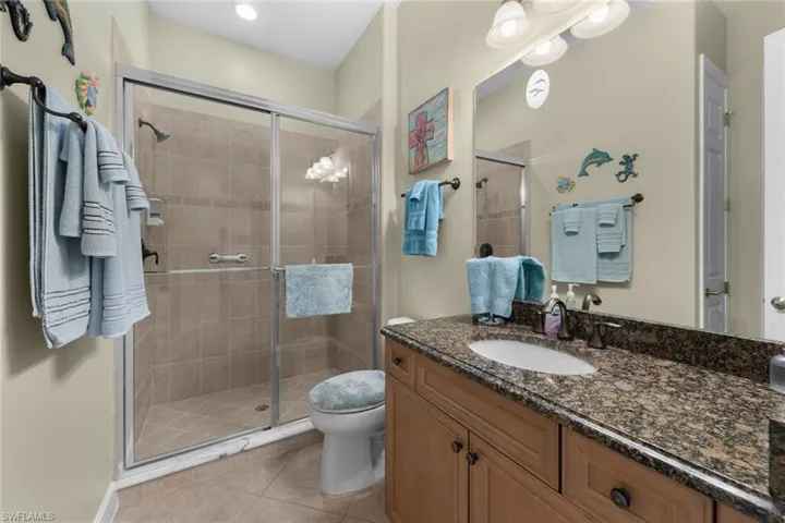 Bathroom featuring vanity, walk in shower, toilet, and tile patterned floors
