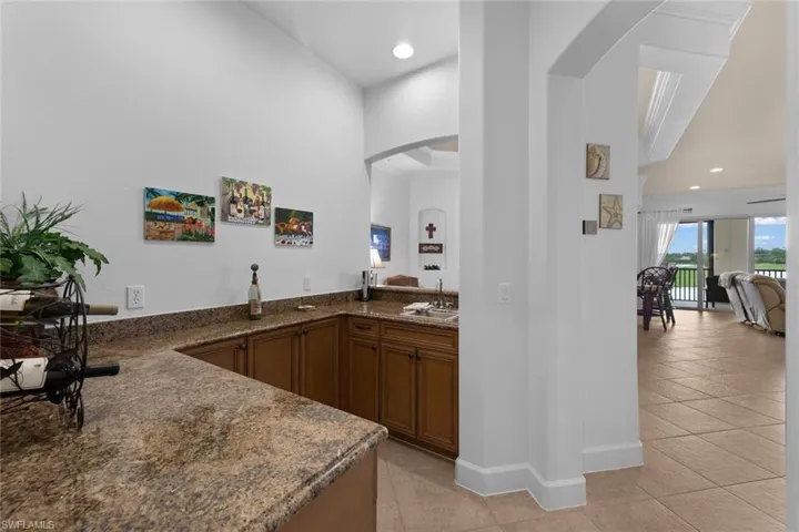 Bar featuring light tile patterned flooring, sink, and dark stone countertops