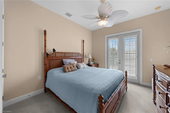 Bedroom featuring light carpet, ceiling fan, and french doors