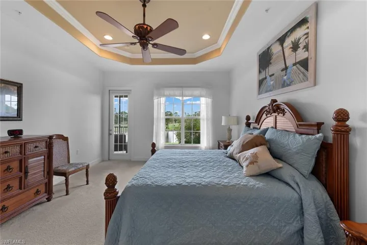 Bedroom featuring light colored carpet, access to outside, ceiling fan, a raised ceiling, and ornamental molding