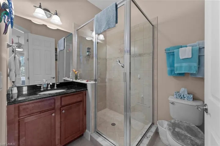 Bathroom with tile patterned flooring, a shower with door, toilet, and vanity