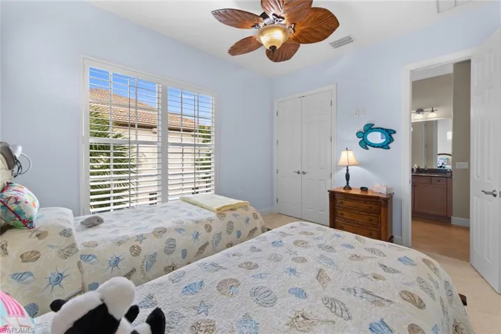Carpeted bedroom with a closet, ensuite bath, and ceiling fan