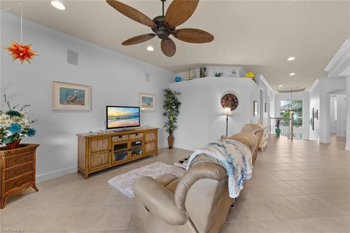 Tiled living room featuring ceiling fan and ornamental molding