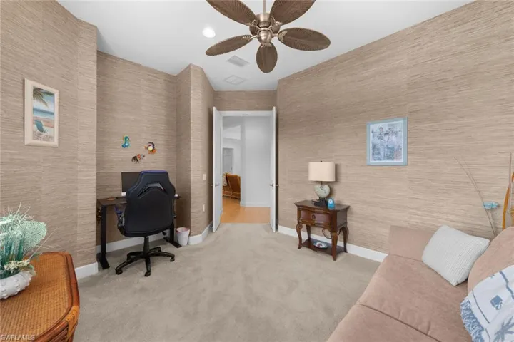 Carpeted home office featuring ceiling fan