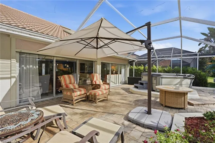 Screened patio featuring a hot tub, tiled roof, sliding glass doors, and paver flooring