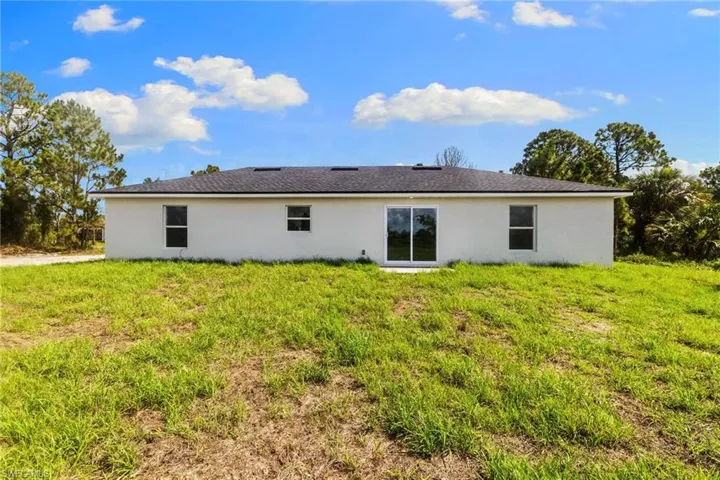 Back of house with stucco siding and a yard