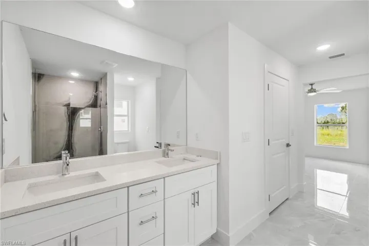Bathroom with marble finish flooring, a shower stall, double vanity, recessed lighting, and ceiling fan