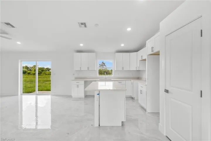Kitchen featuring a center island, light marble finish flooring, light countertops, recessed lighting, and white cabinets
