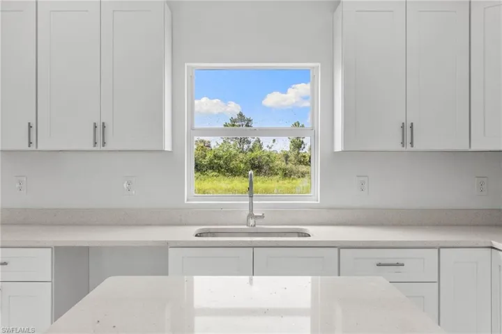 Kitchen with white cabinetry and light stone counters