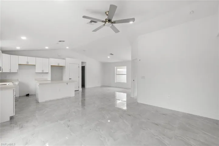 Unfurnished living room featuring vaulted ceiling, ceiling fan, recessed lighting, and light marble finish flooring
