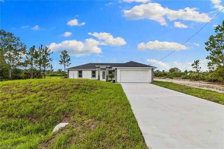 View of front facade featuring driveway, a garage, and stucco siding