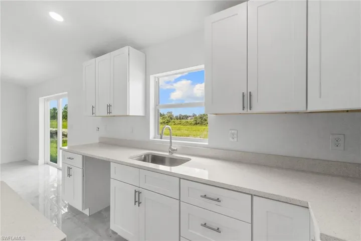 Kitchen featuring white cabinetry, light marble finish floors, recessed lighting, and light stone counters