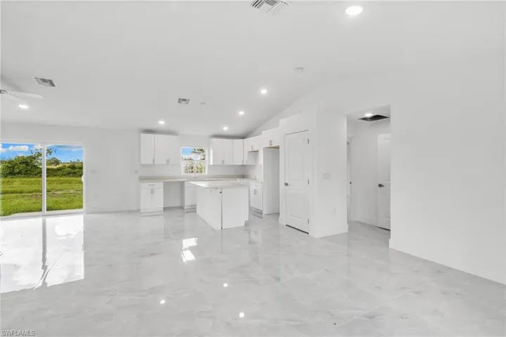 Unfurnished living room with recessed lighting, light marble finish flooring, and vaulted ceiling
