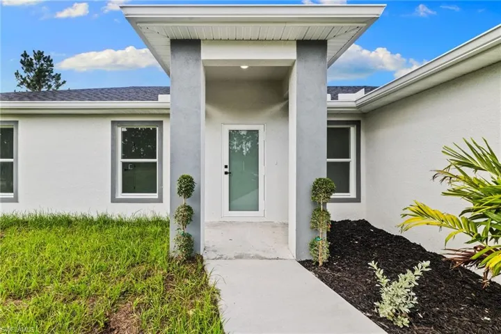 Property entrance with stucco siding and roof with shingles