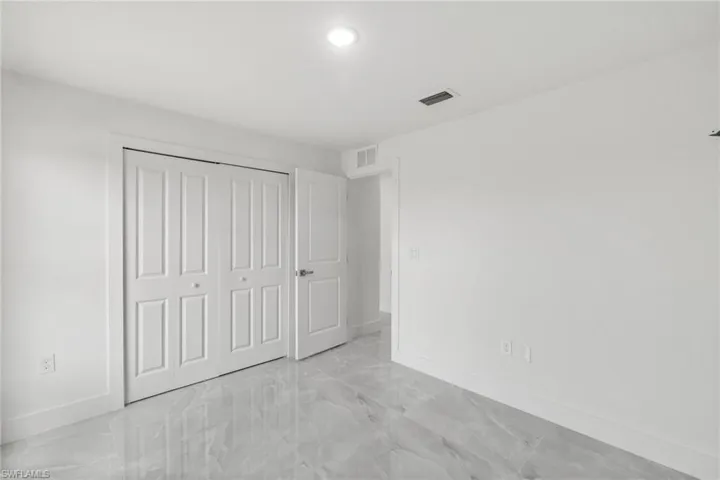 Unfurnished bedroom with light marble finish floors, recessed lighting, and a closet