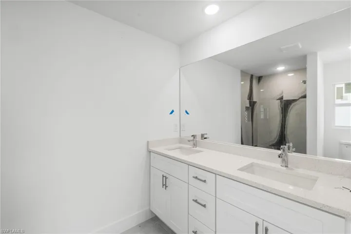 Full bath featuring double vanity, a shower stall, recessed lighting, and tile patterned floors
